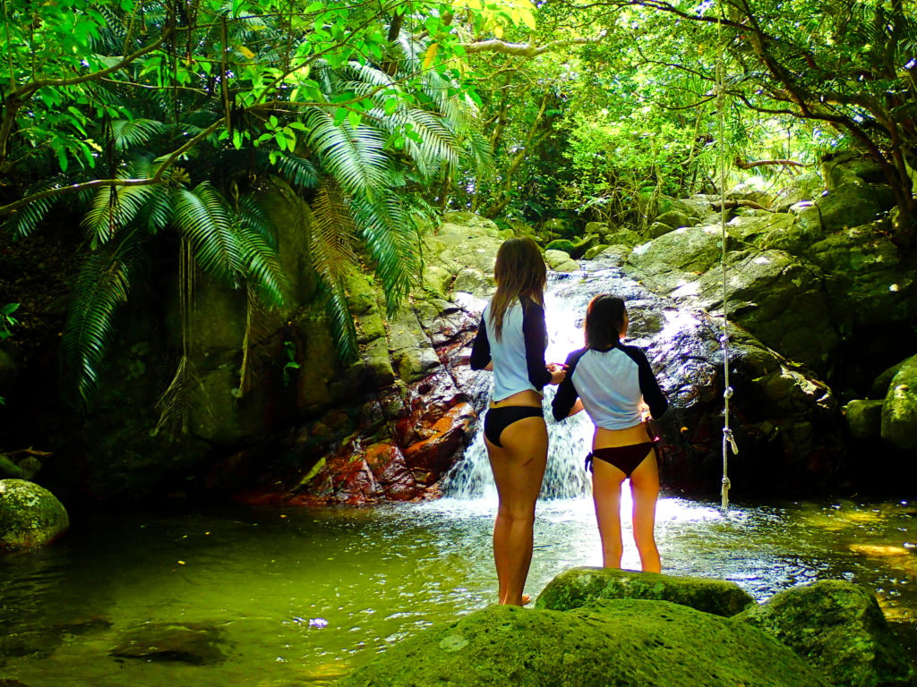 A woman enjoying the waterfalls on Ishigaki Island and the subtropical virgin forest.