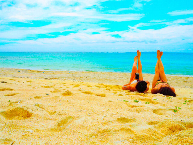 砂浜に寝そべってポーズをとる女性２人