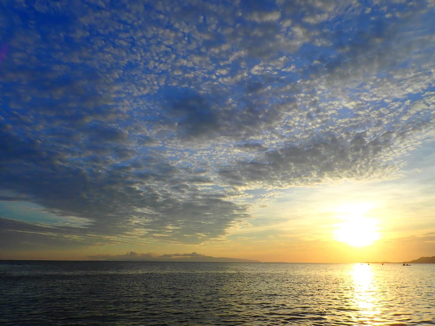 船上から竹富島に沈んでいく夕日を見る