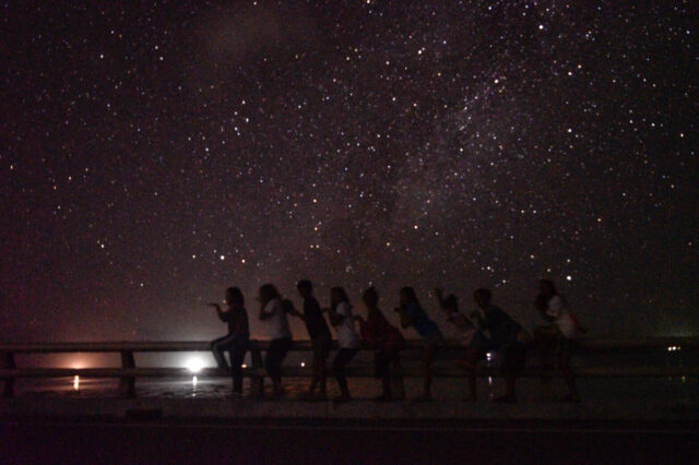 卒業旅行で星空を背景に写真をとる