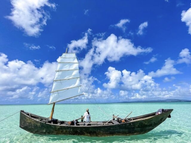 竹富島の海に浮かぶサバニと乗船する人の後ろ姿