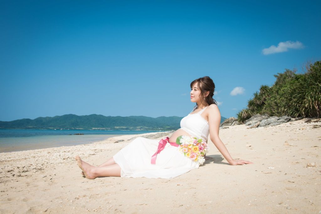 砂浜で座る妊婦