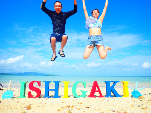 石垣島ハネムーンの最高に楽しい瞬間。ビーチのロゴオブジェの前で全力ジャンプする記念写真。