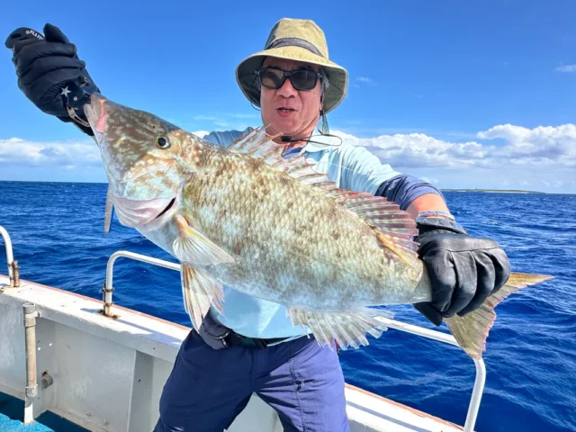 石垣島の釣りスポットで大物のハマフエフキをヒットさせ、満面の笑みを浮かべる釣り人。