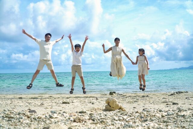 石垣島1泊2日の家族旅行で、青い海を背にビーチでジャンプして楽しむ様子。