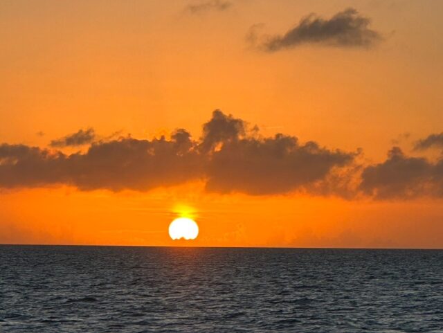石垣島で見る感動的な日の入り。海原の向こうから太陽が昇り、空が深いオレンジ色に染まる風景。