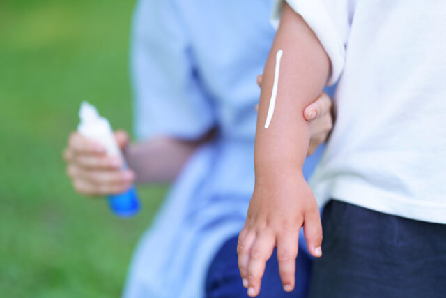 子供に日焼け止めを塗る女性