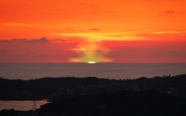 石垣島で撮影された幸運を呼ぶグリーンフラッシュ。真っ赤に染まる夕焼け空の水平線に一瞬だけ現れる緑色の光。