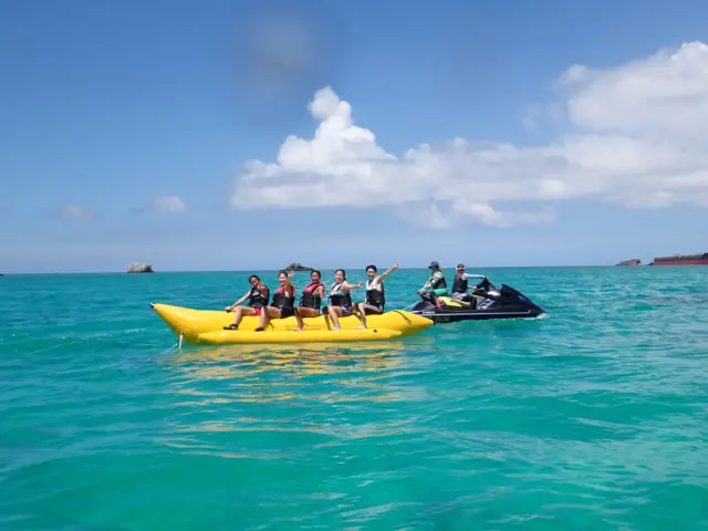 石垣島でバナナボートを牽引する水上バイクと、マリンスポーツを楽しむ観光客。