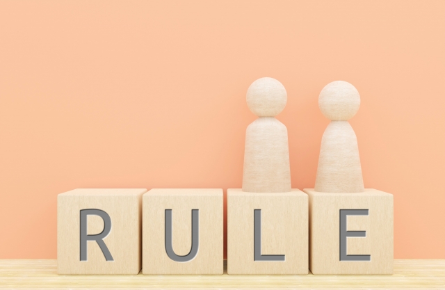 「RULE」と書かれた木製ブロックの上に置かれた2つの人形。