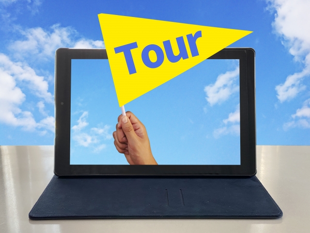 タブレットの画面から、手が「Tour」と書かれた黄色い旗を持っている様子。